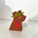 Wooden bear figurine with a green hat and red scarf on a white background
