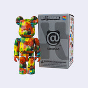 VInyl figure of a Bearbrick styled bear, which resembles a Lego bear character. Its body is covered in a repeating pattern of colorful melty blobs, conjoined together with small faces.