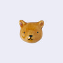 3D ceramic brooch/pin of a brown bear's head with a simplistic cute smile and small eyes.
