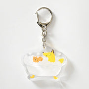 Keychain with cartoon fox taking a bubble bath with cucumbers over his eyes and a small squirrel