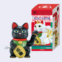 Black wind-up cat toy with a colorful box featuring cartoon cats on a white background