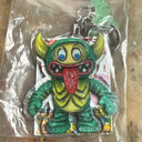 Monster keychain in clear packaging on a wooden surface