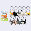 9 different color ways of cat keychains, all smiling with their eyes closed and walking mid-stride with happily curved tails. 