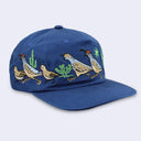 A navy blue baseball cap featuring embroidered quail birds and green cacti on the front panels, set against a light gray background.