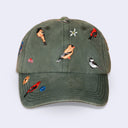An olive green washed cotton baseball cap featuring embroidered birds and small flowers on the front panels and brim, shown against a light gray background.