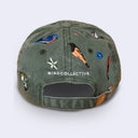 An olive green washed cotton baseball cap featuring embroidered birds, a white flower, and the text 'BIRD COLLECTIVE' on the front, shown against a light gray background.
