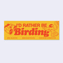 A rectangular yellow bumper sticker with red text reading 'I'D RATHER BE Birding,' plus red line drawings of binoculars and a bird, with small Bird Collective text along the bottom, shown on a light gray background.