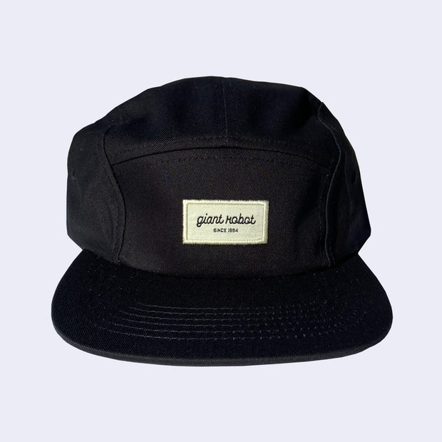 Black 5 panel cap, with a cream colored rectangle embroidering in the center that reads "giant robot' in lowercase cursive and "since 1994" in smaller, caps font below. 