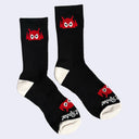 Black socks with a red cartoon robot head on them and cream colored heels and toes. The robot head decorates the cuff end of each sock so that it peeks out when you wear sneakers.