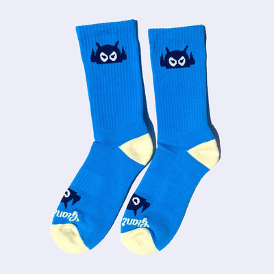 Bright blue socks with a cartoon robot head on them and cream colored heels and toes. The robot head decorates the cuff end of each sock so that it peeks out when you wear sneakers.