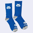 Blue socks with a white cartoon robot head on them and gray colored heels and toes. The robot head decorates the cuff end of each sock so that it peeks out when you wear sneakers.