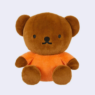 Brown teddy bear with an orange shirt on a light gray background