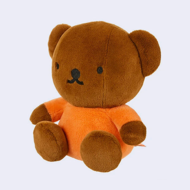 Plush toy bear with brown fur and orange body on a light gray background