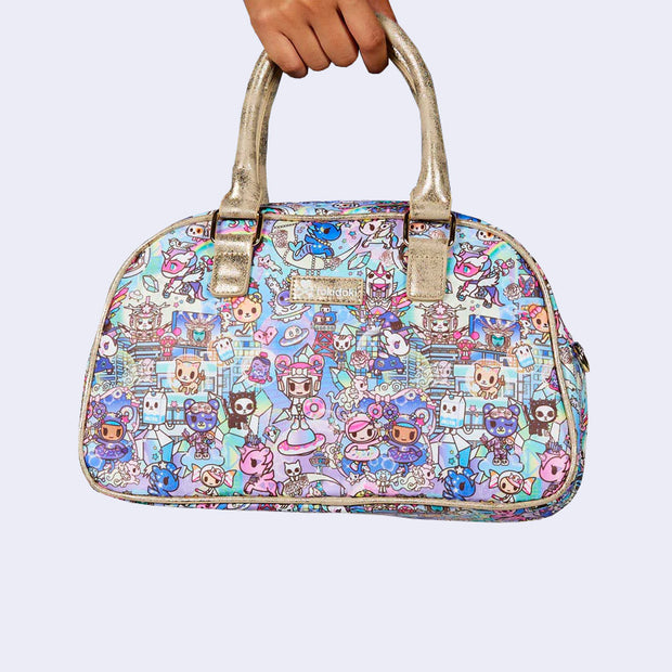 Rounded corner purse with a thick champagne metallic handle. Bag has a small "tokidoki" nameplate on the upper center and is covered completely in a busy colorful pattern featuring tokidoki characters with with galactic and sci fi imagery.