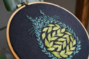Embroidery hoop with silhouette of Totoro, made up of leaves and vines.