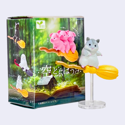 Toy figure of a hamster on a broomstick with packaging in the background