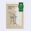 Kraft brown greeting card with an illustration of a cute small dog sitting on a tall stool at a tall table reading a book and smelling a cup of coffee.