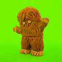 Vinyl figure of a brown yeti covered completely in hair with small pink and white eyes.