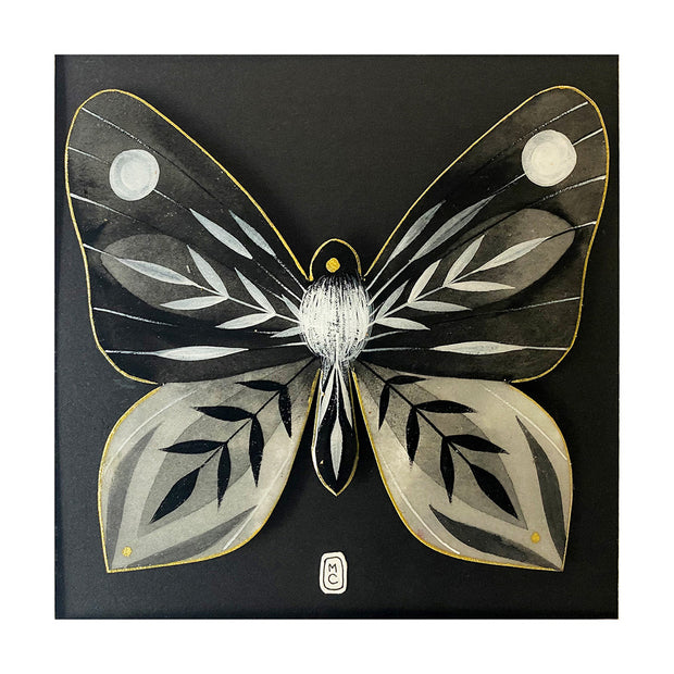 Illustration on cut out paper of a grey, black and white butterfly with abstract striped patterns on its wings, akin to leaves. Its body has white fur on it, like a moth. Butterfly is outlined in gold and mounted on black paper.