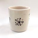 White ceramic cup with black floral design on a white background