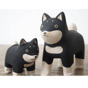 2 small wooden figurines of black and white shiba inu dogs, one is slightly smaller than the other.