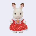 Toy rabbit figure wearing a red dress with white polka dots on a light gray background