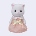White cat figurine with flocked fur, wearing a pink checkered dress and yellow bow on a light gray background