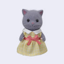 Figurine of a gray cat with flocked fur, wearing a yellow dress with a pink bow around its waist and white collar.