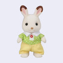 Toy rabbit figure with flocked fur, wearing a green shirt with white polka dots and yellow shorts on a light purple background