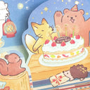 Illustration of a fox blowing out candles on a birthday cake with friends around, including a bear and hedgehog.