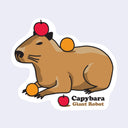 Die cut sticker of a brown capybara laying on the ground with an apple atop its head and a tangerine on its back. At its feet is another tangerine and nearby is another apple. Text below reads "Capybara / Giant Robot"