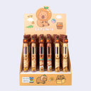 Retractable pens with 6 different colors in one pen, all topped with a rubber capybara figure holding an orange.