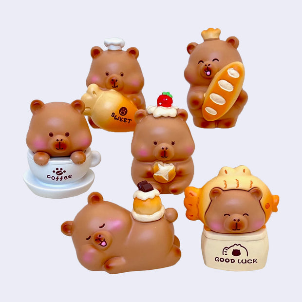 Set of 6 cute capybara figurines with various cafe or bakery themed items on a white background
