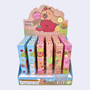 Display of colorful boxes with cartoon capybara designs, each box holds a pen. 