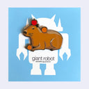 Enamel pin of a brown capybara, laying down with a red apple on its head and a tangerine on its back and between its paws. On blue "Giant Robot" backing board.