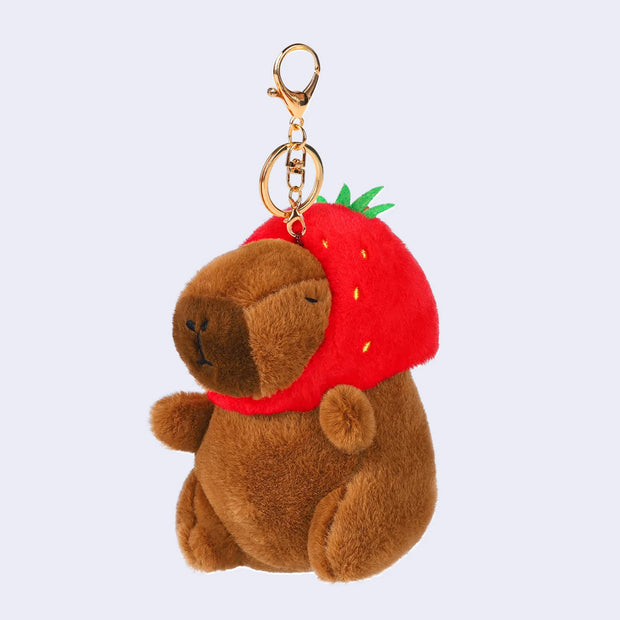 Plush keychain doll of a capybara with a strawberry shaped hood hat.