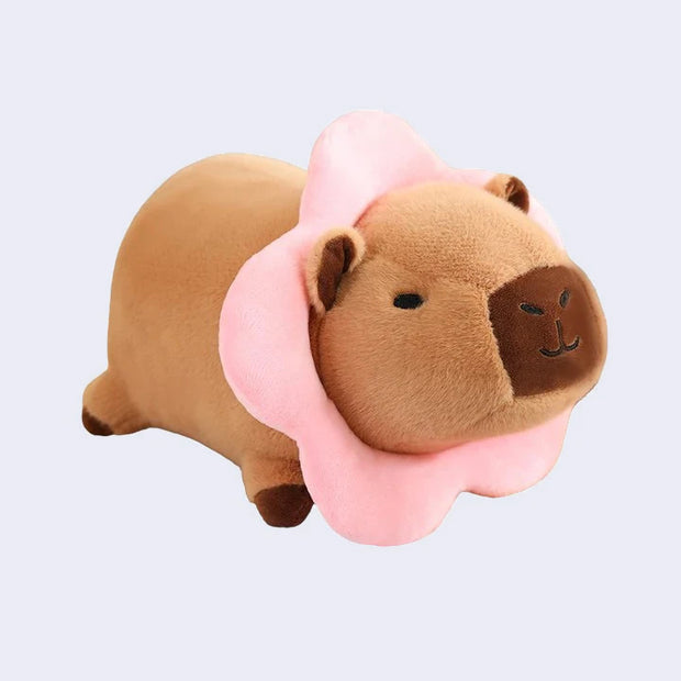 Capybara plush with a pink flower collar around its head.