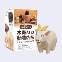 A small white goat-shaped collectible figurine with yellow horns and pink inner ears stands in front of its retail box. The packaging shows multiple animal figurines and Japanese text, with a warning label near the bottom.