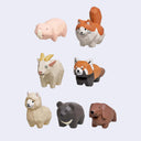 Set of seven low-poly animal figurines including a pink naked mole rat, orange and white cat, cream goat, red panda, beige llama, dark gray bear, and brown wombat, arranged on a light gray background.