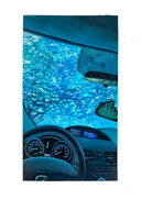 Painting of the inside of a car going through a car wash, with blue soap illuminating the car.