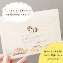 Envelope with cute illustrations of a cat, and a brown stamped cat design on the seal, held by a hand against a gray background.