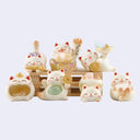 Set of small cat figurines with various poses and accessories on a light purple background
