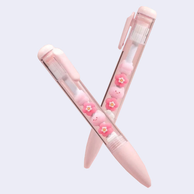 2 pink pens with clear bodies that show sakura flowers inside and small cat heads.
