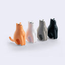 Four cat-shaped figurines in different colors on a white background