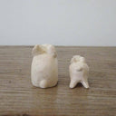 Two white wood figurines of rabbits, one is slightly larger than the other.