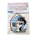 Air freshener with cartoon design of a girl with angel wings sitting inside of a very small house, crouched with her knees pulled into her chest.