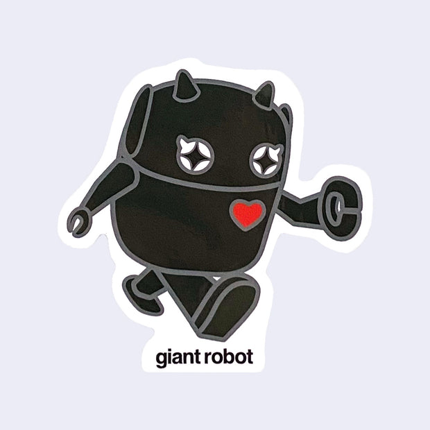 Die cut sticker of a small, chibi style black robot with a red heart on its right chest, in the action of walking. Below, "Giant Robot" is written in lowercase black font.