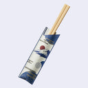 A pair of light wood chopsticks resting inside a decorative paper sleeve with a blue and white Japanese wave and sun design, set against a light gray background.