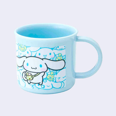 Small blue plastic cup with a mug handle featuring an illustration of Sanrio's Cinnamoroll, wearing a sling style bag shaped like a chick. Behind, is a patterned background of Cinnamoroll and a small yellow chick. 
