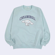 Baby blue pull over sweater featuring a graphic of Cinnamoroll, looking back over her shoulder and waving. Above, written in outlined capitalized letters says "Cinnamoroll".